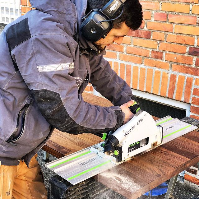 Tømrer som saver i brune planker